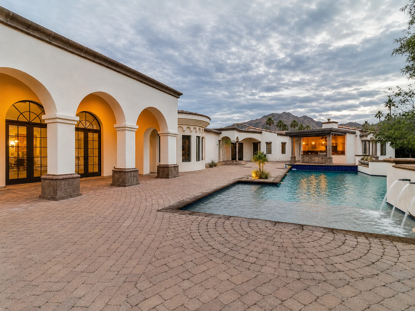 Pool courtyard with mountain views and warm exterior lighting