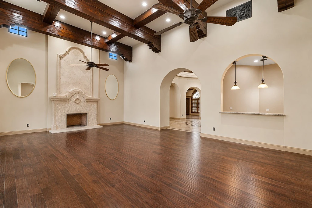 Unfurnished great room with fireplace, beams, and arched openings