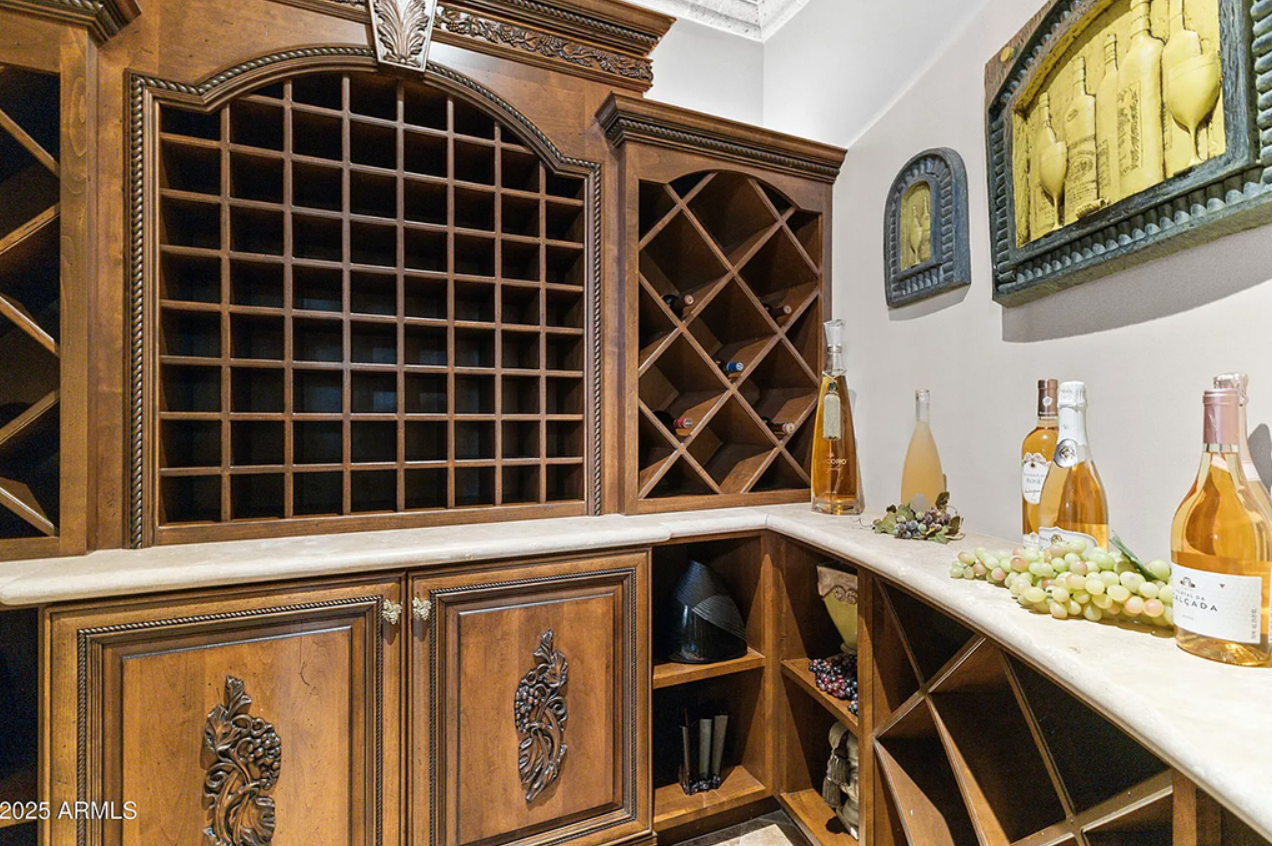 Custom wine room with carved wood storage, stone counters, and display bottles